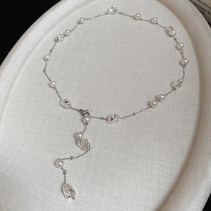 Dettaglio di perle irregolari e sfere d'argento su una catena sottile su vassoio