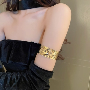 Detailed macro view of gold-finished metallic upper arm cuff with hammered texture finish