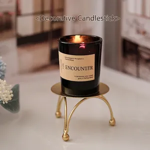 European gold iron candle holder with a black glass scented candle on a tripod stand