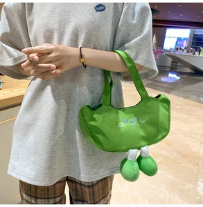 Detail of green canvas tote bag featuring cute cartoon face and 3D plush legs decoration