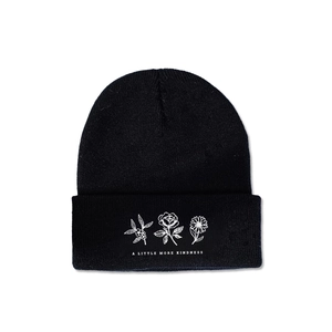 Detail of black knit beanie with white floral embroidery and kindness lettering