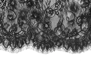 Close-up of black floral lace fabric with delicate eyelash trim details for a dress