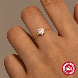 S925 sterling silver heart ring with gold chain and pink stone on a finger