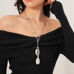 Detail shot of a silver necklace featuring a sparkling rhinestone-studded sunglass pendant