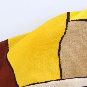 Dettaglio macro del tessuto a motivi geometrici giallo e marrone per set camicia