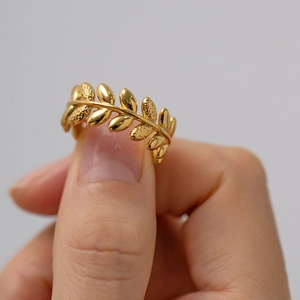 Close-up of a golden olive branch ring on finger with detailed leaf craftsmanship