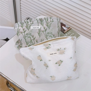 Detailed close-up of floral embroidery on makeup bags with simple wish label and zipper
