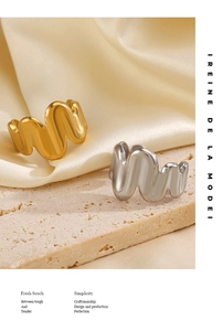 Detailed close-up of gold and silver wavy stackable rings on stone and silk background