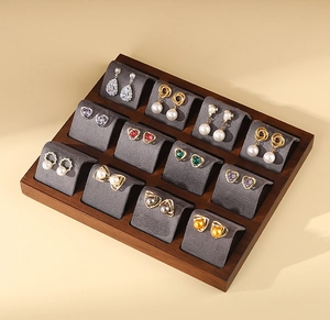 Macro shot of walnut earring display tray with grey velvet lining and pearl jewelry