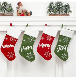Close-up of four red and green plush Christmas stockings with snowflakes on a white mantel