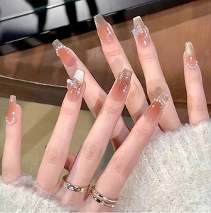 Close-up of blush press-on nails with 3D butterfly and cat-eye finish.