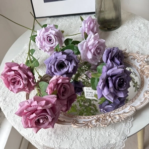Close-up of artificial diamond roses in deep purple and soft pink on a lace tablecloth