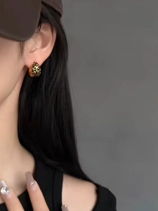 Close-up of leopard print geometric sphere earring on model ear with gold finish