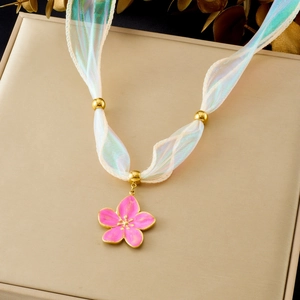 Detailed view of pink cherry blossom pendant with gold edges and white ribbon necklace