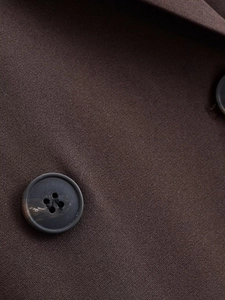 Detailed macro view of dark brown blazer fabric texture and black resin buttons