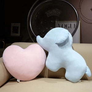 Coussins en peluche cœur et éléphant rose et bleu sur un canapé en tissu beige