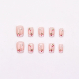 Pink French press-on nails with red cherry hand-painted designs and small rhinestones