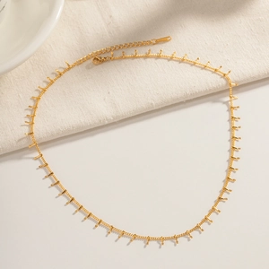 Flat lay of 18K gold-plated stainless steel bar chain necklace on linen and ceramic