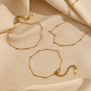Three 18K gold plated stainless steel link bracelets on elegant beige silk fabric