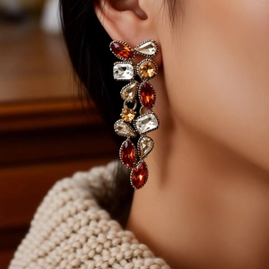 Close-up of vintage bronze earrings with red and amber crystals on female model