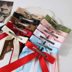 Handmade double-layered satin ribbon bow hair clips with long streamers on a white tray