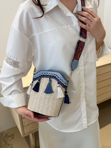Detail of bohemian straw bucket bag with blue fringe tassels and geometric strap