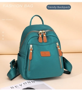 Detail of teal nylon mini backpack with leather logo patch and multiple zipper pockets