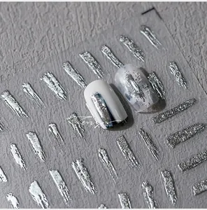 Macro shot of silver metallic brushed nail stickers with artistic ink textures