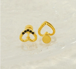 Macro detail of gold heart stud earrings with black crystals and screw back structure