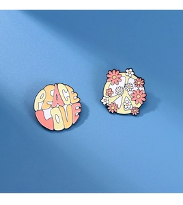 Detail of peace love enamel pin set with floral peace sign on a blue background