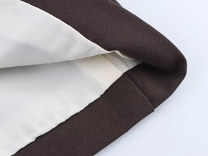 Close-up of deep brown suit jacket sleeve with ivory lining and premium stitching