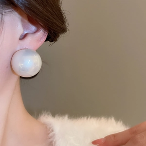 Gros plan d'une grande boucle d'oreille perle ronde sur mannequin pour un look élégant