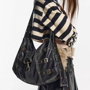 Macro detail of black vintage leather hobo bag featuring silver buckles and rivet studs