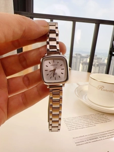 Silver square ladies quartz watch with a sleek link bracelet held against a city view