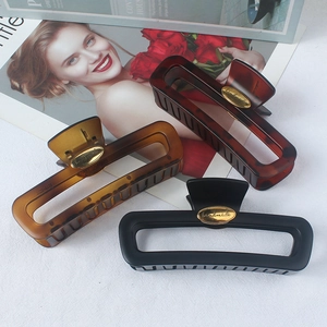 Three hollow square hair claws in leopard, amber, and matte black styles shown on a magazine