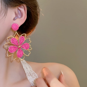 Detail von großem Bast-Blumenohrring mit goldenem Metallrahmen, getragen am Model