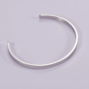 Macro detail of high-polished stainless steel C-shaped cuff bracelet with rounded ends