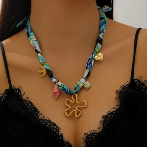 Détail du collier foulard en soie avec pendentifs dorés de fleurs, oiseaux et coquillages