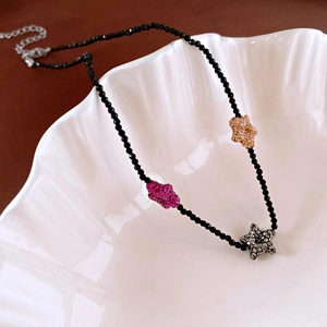 Detail of beaded necklace with colorful crystal star pendants on shell display plate