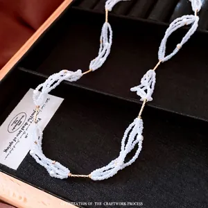 Elegant multi-strand white glass pearl necklace with gold metal tubes in a jewelry box