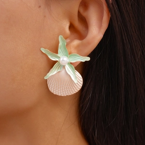 Close-up of mint starfish and pink shell earrings with pearl on a model's ear