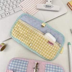Close-up of quilted fabric organizer pouch showing metal snap button and earphone storage space
