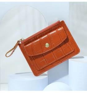 Detail of orange crocodile pattern leather card holder with top zipper and front snap pocket
