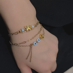 Three-layer 18K gold plated titanium bracelet with butterfly, pearl, and evil eye charms