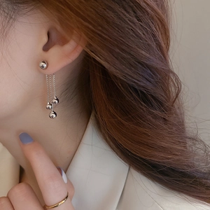 Detail of silver drop earrings with metallic beads and tassels on a female model