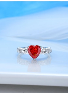 Macro shot of silver ring with red heart-shaped gemstone and side diamond accents