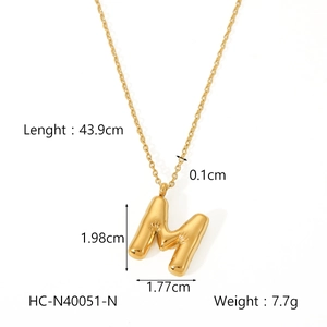 Detail view of golden puffy letter M pendant showing 43.9cm length and 7.7g weight