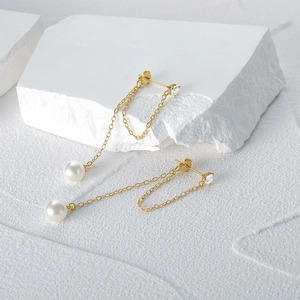 Detail of s925 silver tassel chain earrings with white pearls and gold finish