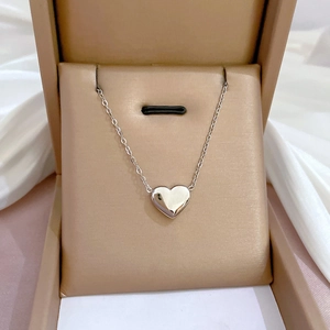 Vue détaillée du collier pendentif cœur poli sur velours beige dans un écrin de luxe