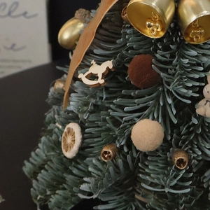 Mini Christmas tree ornament with golden bells and wooden horse on pine branch